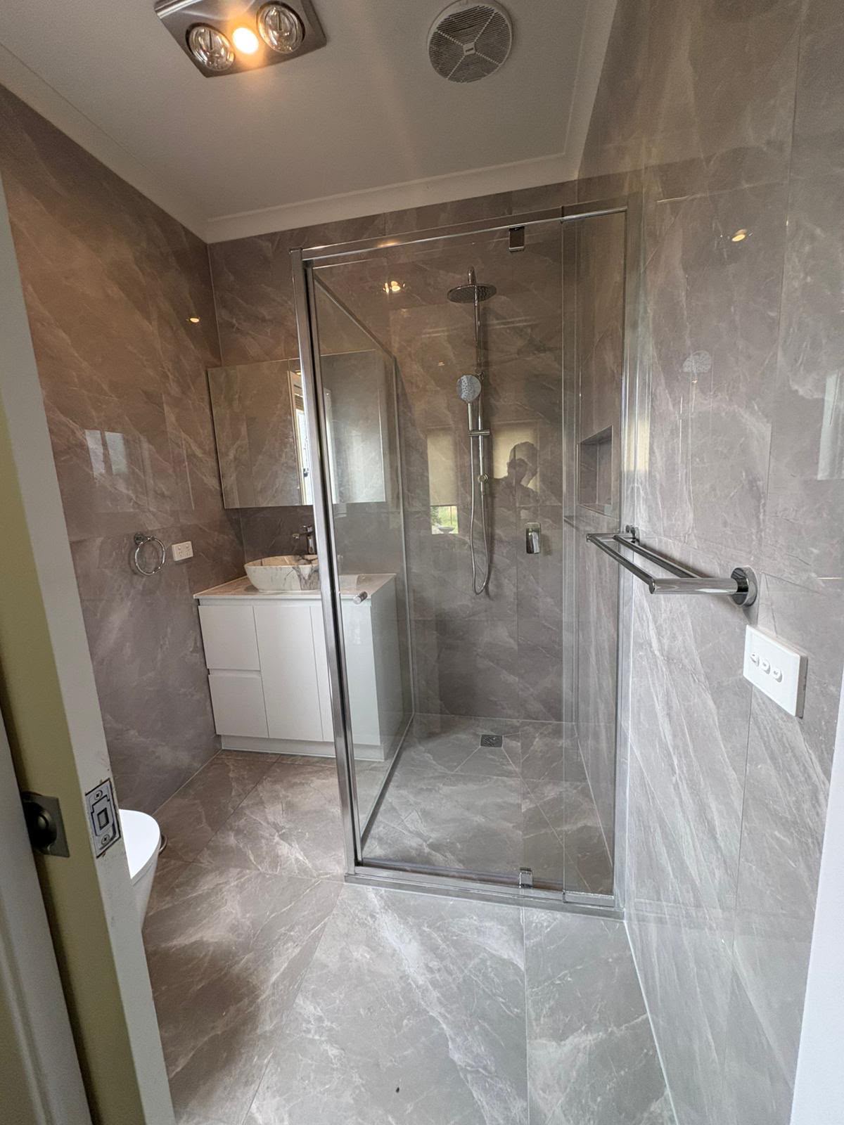 Grey marble-look bathroom with chrome framed shower, vessel basin and matching floor tiling