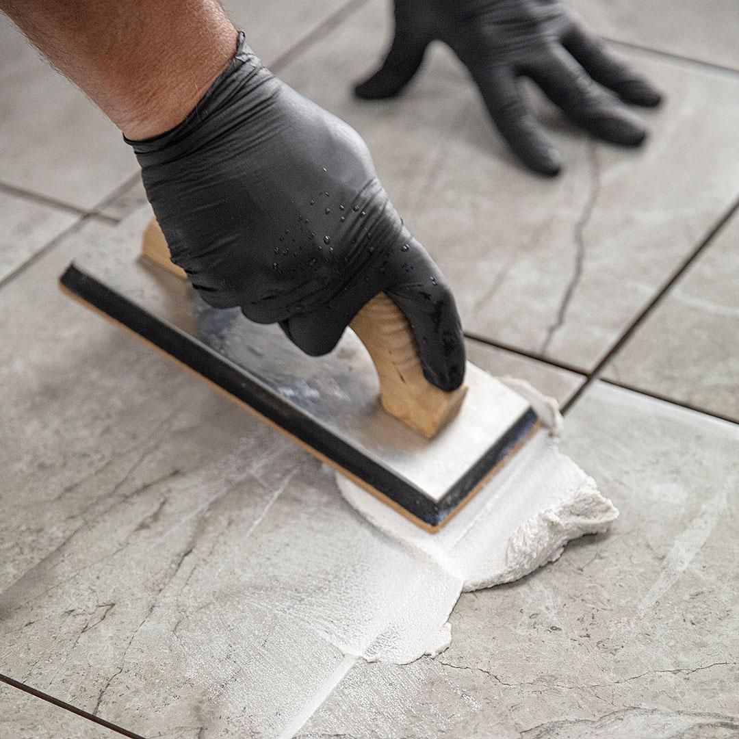 Tiler grouting large format floor tiles by hand